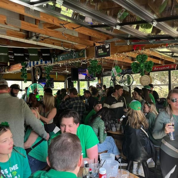 A lively crowd of people in green attire celebrating St. Patrick's Day at Trooper Thorn's Irish Beef House.