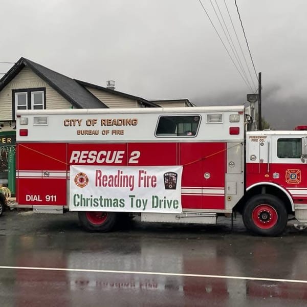 A red and white fire truck with a "Reading Fire Christmas Toy Drive" banner on its side.