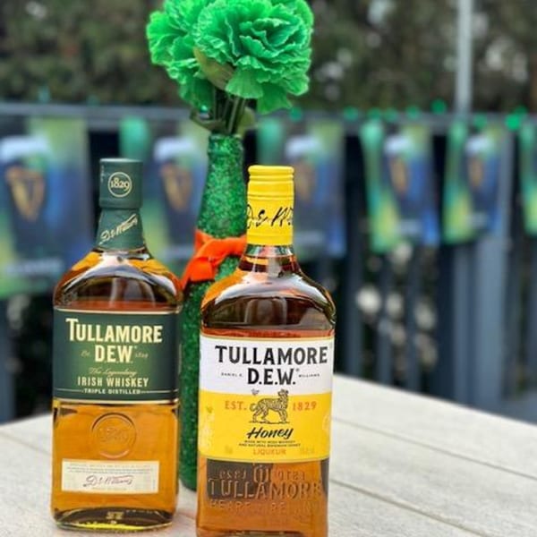 Two bottles of Tullamore D.E.W. Irish whiskey and honey liqueur on a table with green decor.