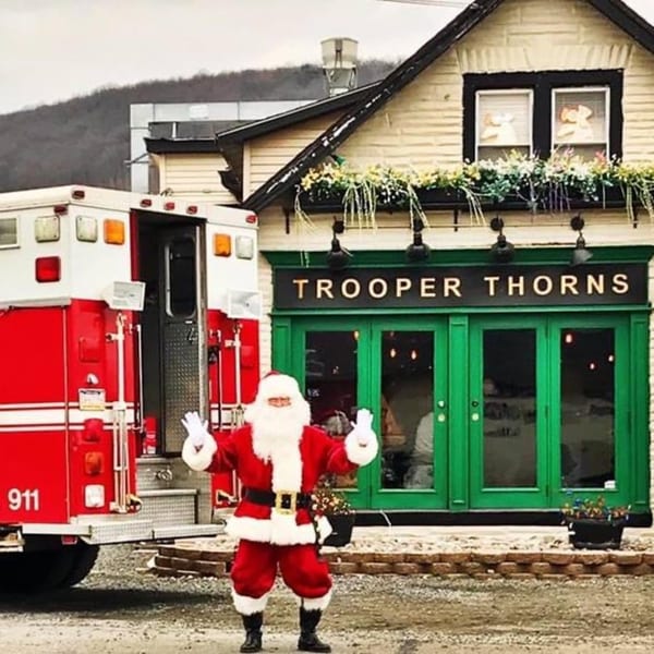 Santa Claus stands in front of Trooper Thorn's Irish Beef House with a fire truck nearby.